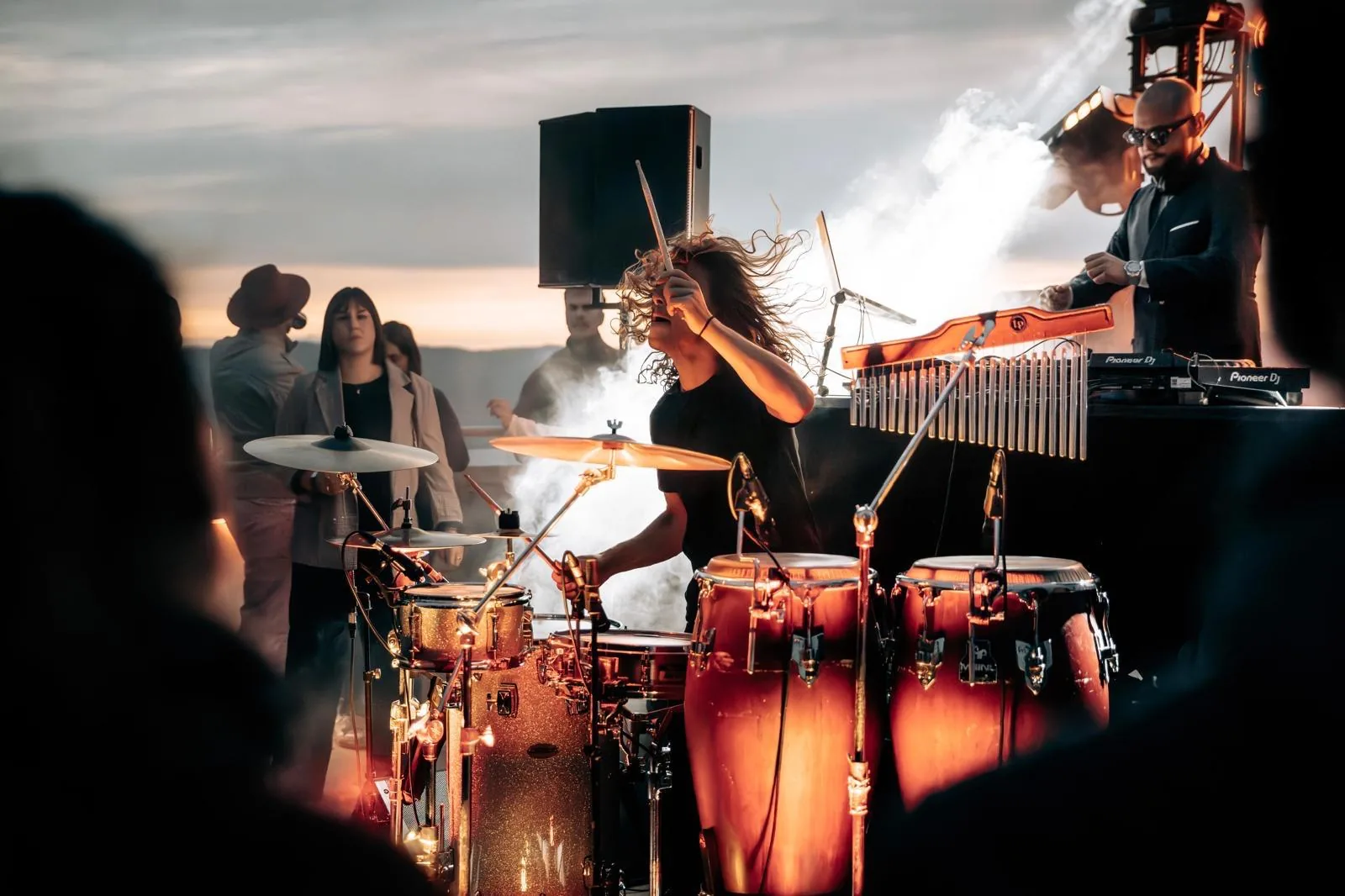 Cyrille, percussionniste du réseau, à la batterie face au coucher de soleil pendant un set