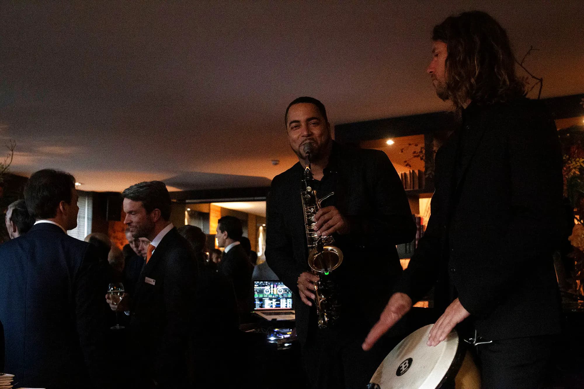 Saxophoniste et percussionniste jouant entre les tables pendant un cocktail d'entreprise