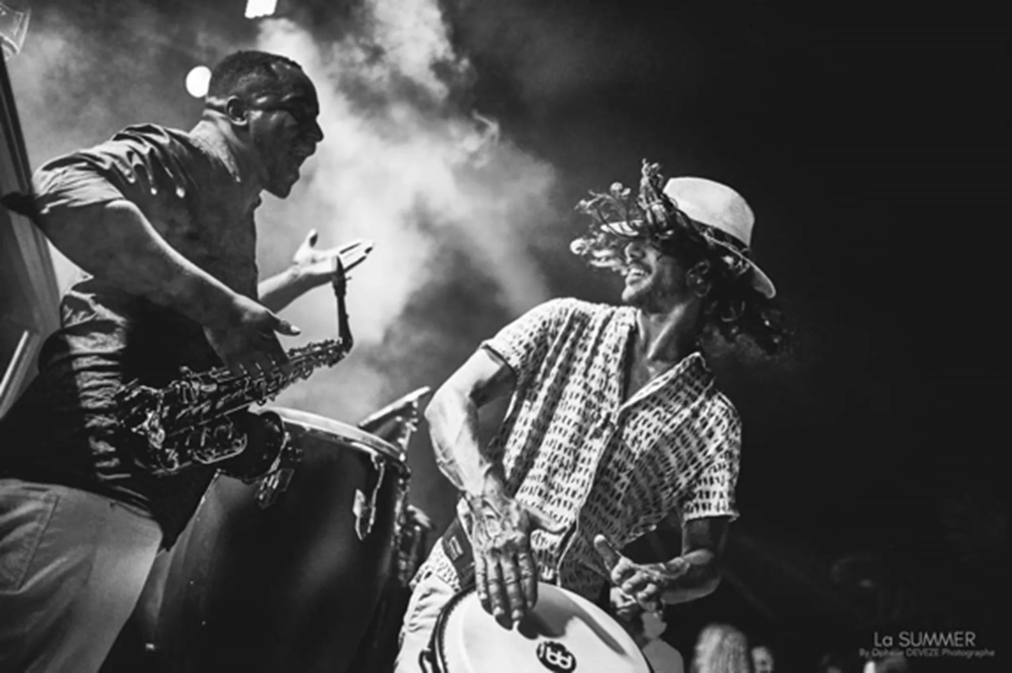 Saxophoniste et percussionniste en contre-jour dans la fumée d'une scène